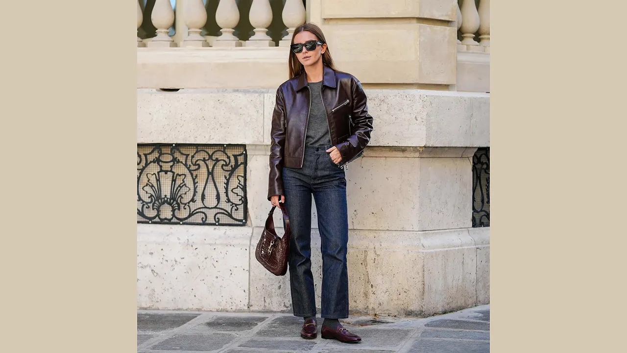 Woman wearing dark straight-leg jeans with a dark leather jacket and brown shoes